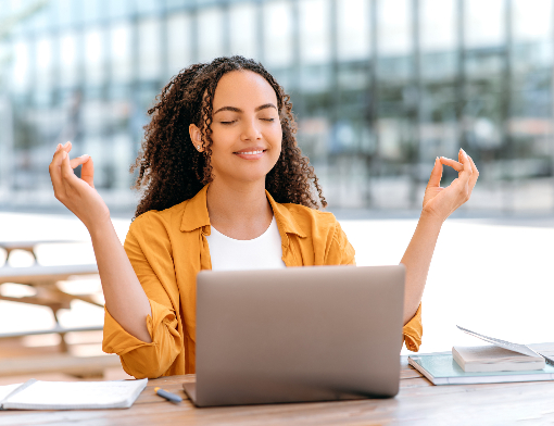 Aluna praticando meditação para estudos na frete de seu notebook